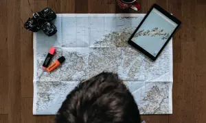 Planerar en resa ensam. Karta, kamera, surfplatta och överstrykningspennor ligger redo.
