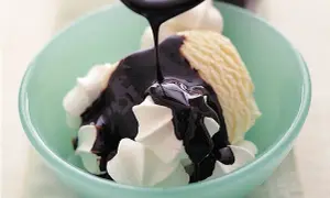 En skål med vaniljglass och visp täcks av glansig chokladsås. Ett perfekt chokladsås recept för en lyxig dessert.