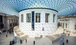 Storslagen arkitektur i London, med en imponerande glasstruktur som tak. En rund byggnad med trappor leder uppåt, omgiven av klassiska pelare. Här finns konst och historia att utforska.