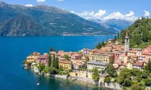 Färgstark by vid en blå sjö i norra Italien, med gröna berg i bakgrunden.