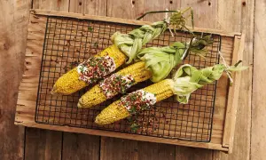 Grilla majskolv med krämig topping och chili. Majskolvarna är vackert inslagna i sina egna blad.