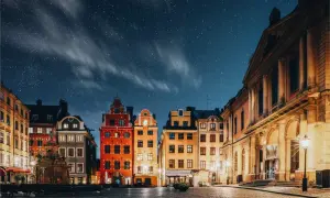 Stokholm stare miasto under en stjärnklar natt. Färgglada hus och kullerstensgator lyser upp torget.