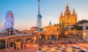 Tivoli i solnedgången med pariserhjul, karusell och en imponerande kyrka. Perfekt för Barcelona aktiviteter med familjen.