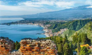 Vacker vy över kusten vid Catania, Sicilien, med det blå havet, en stad längs kusten och Etna i bakgrunden.