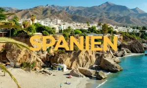 Varmast i Spanien: en solig strand med turkost vatten, klippor och vita hus i bakgrunden.