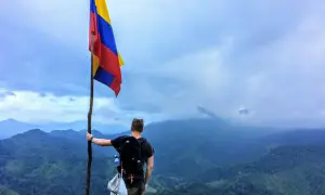 Vandrare med Colombias flagga på en bergstopp. Trots att en resa till Colombia kan verka farligt, bjuder landet på otroliga vyer.