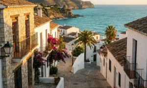En charmig gränd med vita hus och bougainvillea leder ner mot det turkosblå havet. En idyllisk vy av Spanien på vintern.