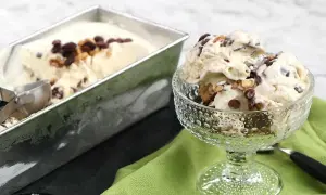 En skål med krämig nicecream banan, toppad med chokladbitar och nötter. Bredvid står en form med mer glass.