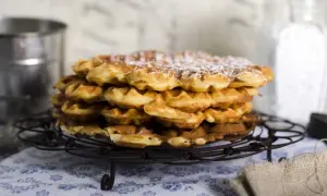 En hög med fluffiga, gyllene frasvåfflor, pudrade med florsocker. Perfekt för ett mysigt fika.