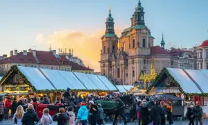 En livlig prag julmarknad med folk, häst och vagn, och en kyrka i bakgrunden.