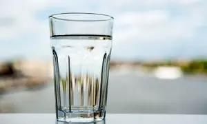 Ett glas med klart vatten står på ett bord. Frågan är om kan man dricka kranvatten i Tyskland?