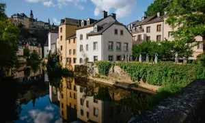 Vackra hus längs en flod i Luxemburgs huvudstad, med speglingar i vattnet.