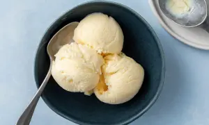 Tre skopor krämig vaniljglass i en mörkblå skål med en sked. Perfekt för ett enkelt gelato recept.