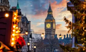 Big Ben lyser upp en magisk london julmarknad. Julgranar med ljus och vackra byggnader skapar en festlig stämning i solnedgången.
