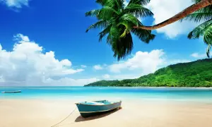 En blå båt på en sandstrand med palmer och turkost vatten. En dröm om Maldiverna eller Mauritius.