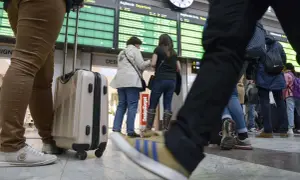 Resenärer med bagage vid en avgångstavla. Kanske dags att fundera på ving av och ombokningsskydd för resan.
