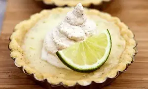 En liten key lime pie med en klick grädde och en limeklyfta.