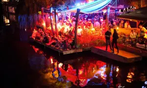 Folk festar på en flytande nattklubb i Berlin. Ljusen reflekteras i vattnet.
