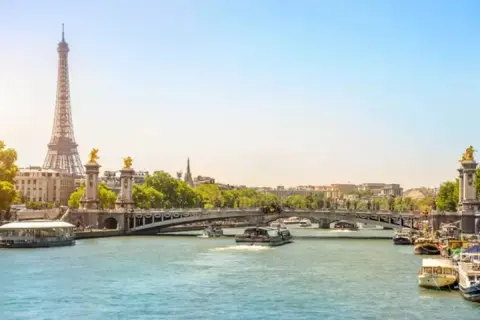 Eiffeltornet och Pont Alexandre III över Seine. En perfekt vy för en minnesvärd resa, kanske **2 dagar i Paris**? Båtar glider fram på vattnet.