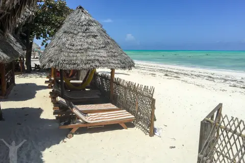 Soliga solstolar och hängmattor under halmtak vid en turkos strand. Drömmer du om en resa till Zanzibar? Pris kan variera, men detta ser ut som paradiset.