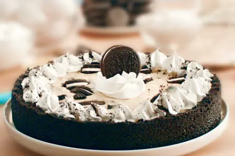 En krämig oreo cheesecake med vispgrädde och krossade oreos.