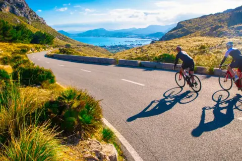 Två cyklister njuter av en solig dag med att cykla på Mallorca, med en vacker vy över havet och bergen.