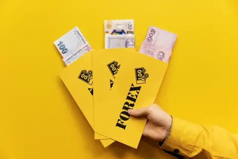 En hand håller gula kuvert märkta "FOREX" med sedlar från Turkiet, Storbritannien och Thailand.