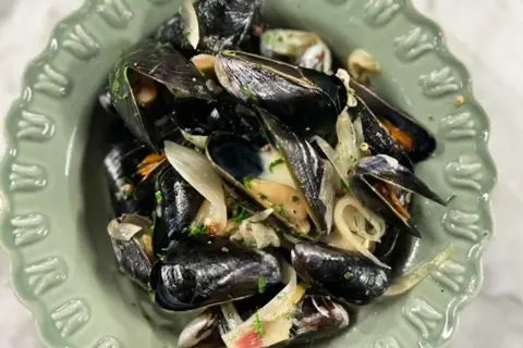 En skål med ångade musslor och lök, perfekt för ett enkelt musslor recept.