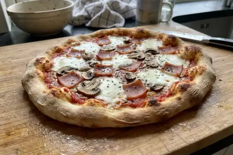 En hemgjord pizza med skinka och champinjoner, perfekt för ett mysigt hemmakväll. Ett enkelt hemgjord pizza recept att prova!