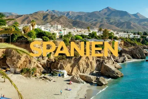 Varmast i Spanien: en solig strand med turkost vatten, klippor och vita hus i bakgrunden.