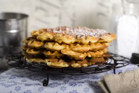 En hög med fluffiga, gyllene frasvåfflor, pudrade med florsocker. Perfekt för ett mysigt fika.