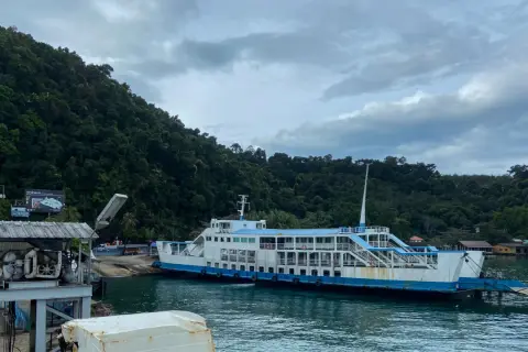 Färja anländer till Koh Chang. Gröna berg och molnigt himmel.