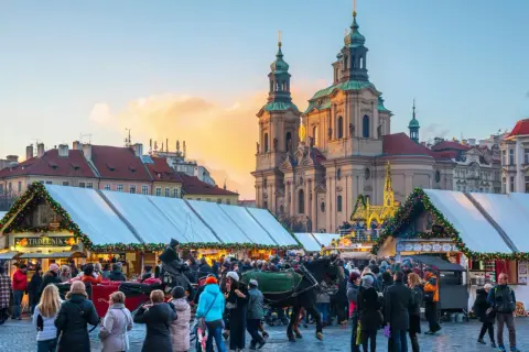 En livlig prag julmarknad med folk, häst och vagn, och en kyrka i bakgrunden.