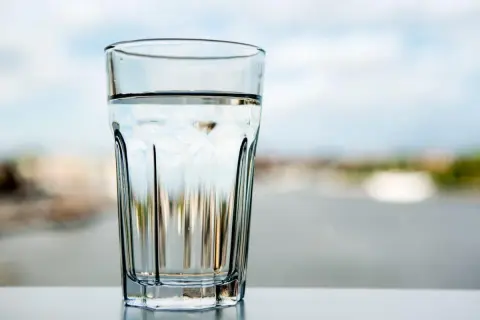 Ett glas med klart vatten står på ett bord. Frågan är om kan man dricka kranvatten i Tyskland?