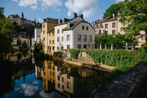 Vackra hus längs en flod i Luxemburgs huvudstad, med speglingar i vattnet.