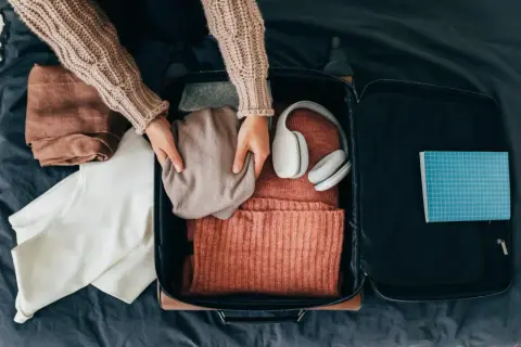 Packa smart! Här ser du vad som kan vara bra att ha i handbagaget på flyget: kläder, hörlurar och en anteckningsbok.