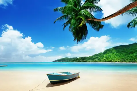 En blå båt på en sandstrand med palmer och turkost vatten. En dröm om Maldiverna eller Mauritius.