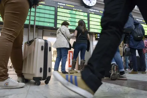 Resenärer med bagage vid en avgångstavla. Kanske dags att fundera på ving av och ombokningsskydd för resan.
