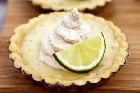 En liten key lime pie med en klick grädde och en limeklyfta.