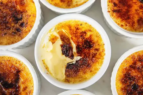 Flera krämiga creme brulee-desserter med karamelliserat sockerlock.