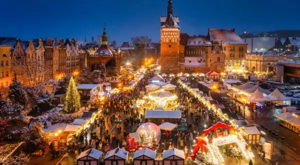 En livlig julmarknad i Gdansk med snö, julgranar och tusentals besökare som njuter av den magiska stämningen.