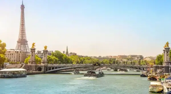 Eiffeltornet och Pont Alexandre III över Seine. En perfekt vy för en minnesvärd resa, kanske **2 dagar i Paris**? Båtar glider fram på vattnet.