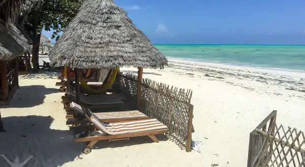 Soliga solstolar och hängmattor under halmtak vid en turkos strand. Drömmer du om en resa till Zanzibar? Pris kan variera, men detta ser ut som paradiset.