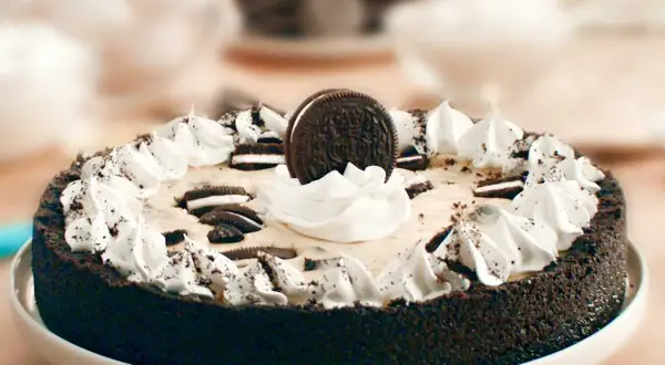 En krämig oreo cheesecake med vispgrädde och krossade oreos.