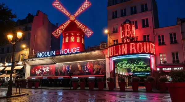Moulin Rouge, en ikonisk nattklubb i Paris, lyser upp natten med sina neonskyltar och röda väderkvarn.
