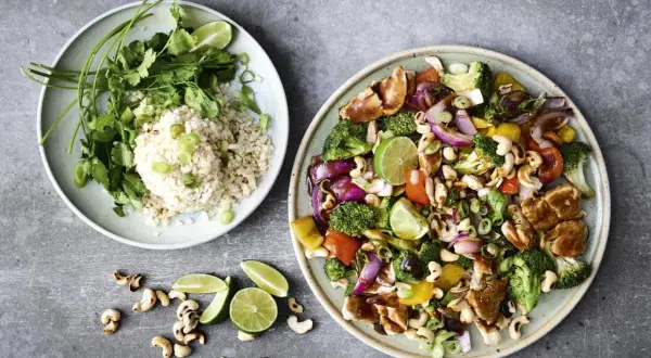 Två tallrikar med mat, en med ris och koriander, den andra med kyckling, grönsaker och cashewnötter. Perfekta middagsidéer!
