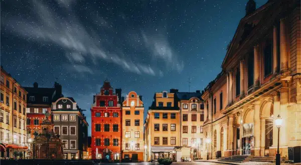 Stokholm stare miasto under en stjärnklar natt. Färgglada hus och kullerstensgator lyser upp torget.