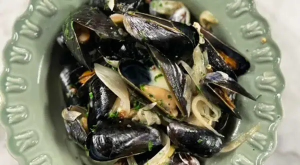 En skål med ångade musslor och lök, perfekt för ett enkelt musslor recept.