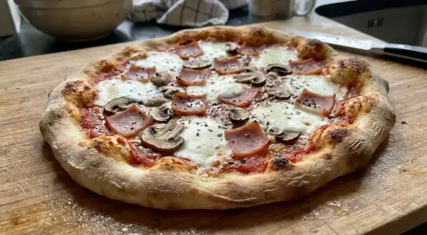 En hemgjord pizza med skinka och champinjoner, perfekt för ett mysigt hemmakväll. Ett enkelt hemgjord pizza recept att prova!