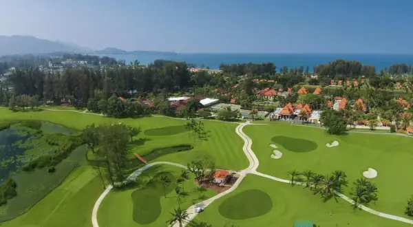 Vacker golfbana i Thailand med gröna fairways, vattenhinder och tropiska träd. En dröm för golfentusiaster.